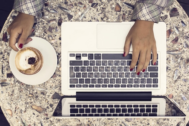 Menina com laptop e tomando café