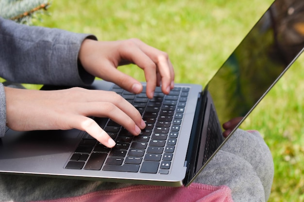 Menina com laptop na grama verde Educação remota A criança trabalha no computador