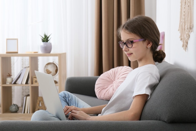 Menina com laptop no sofá em casa