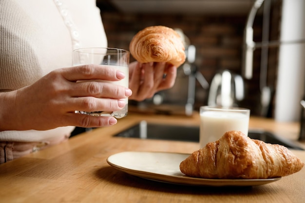 Menina com leite e croissants no café da manhã