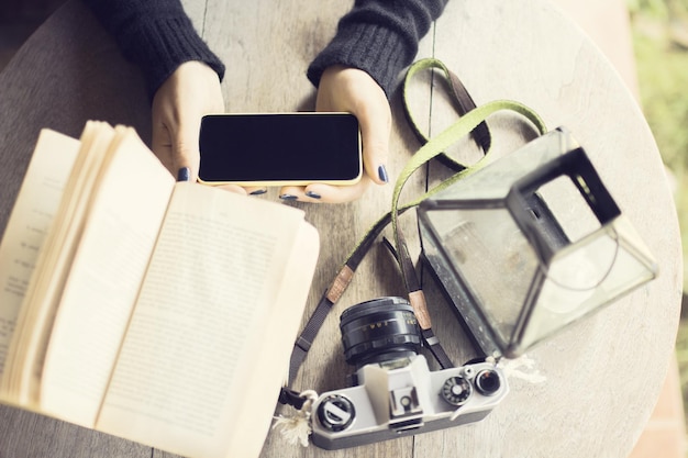 Menina com livros de telefone celular e câmera antiga