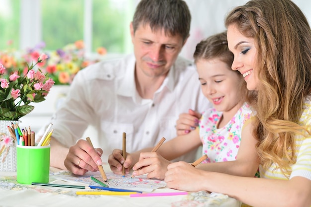 Menina com mãe e pai desenhando em casa