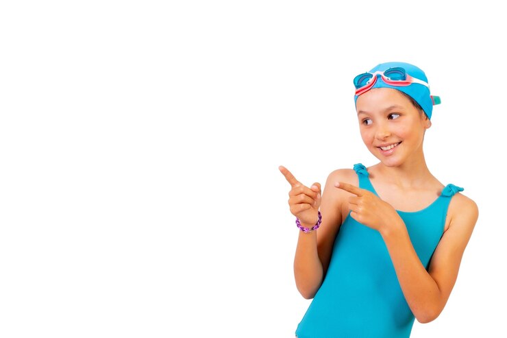 Foto menina com maiô e óculos de mergulho aulas de natação na piscina apontando para o fundo branco esquerdo com espaço de cópia