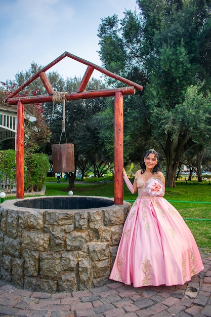 Menina com maquiagem e penteado em um vestido de princesa, perto de um poço dos desejos