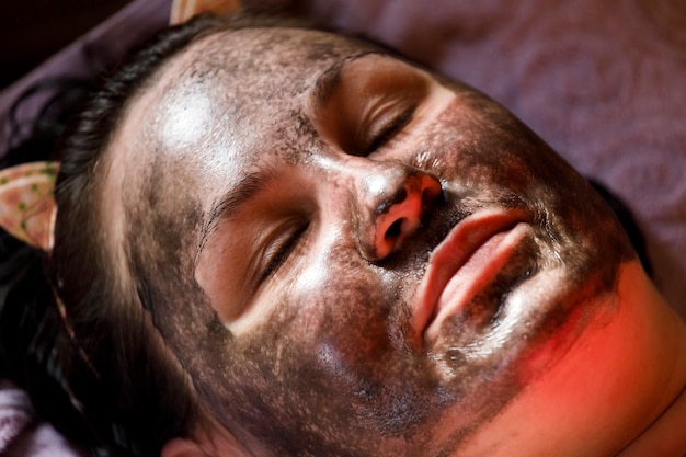 Menina com máscara facial de lama terapêutica. procedimento cosmético para o rosto. rejuvenescimento da pele. Foto de alta qualidade