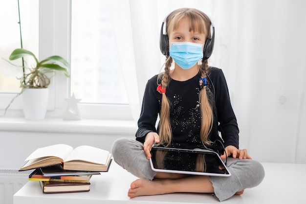 menina com máscara médica estudando em casa. epidemia, pandemia.