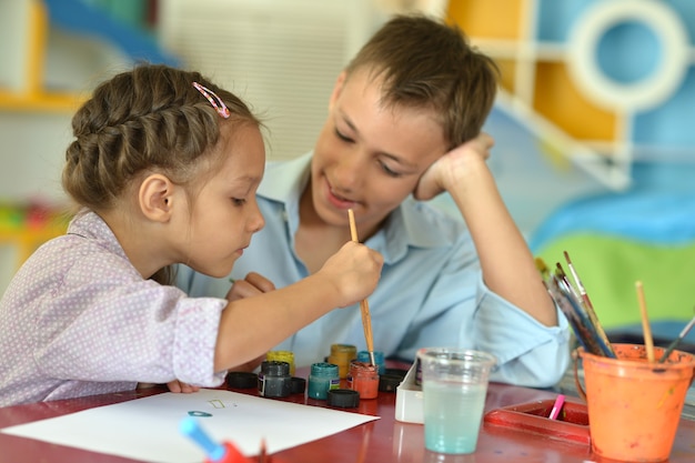 Menina com menino desenhando em casa