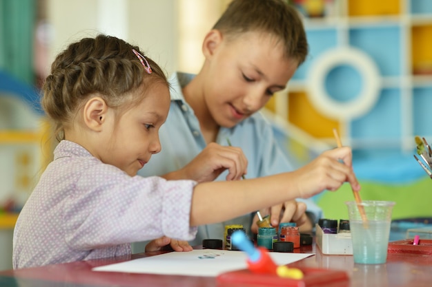 Foto menina com menino desenhando em casa