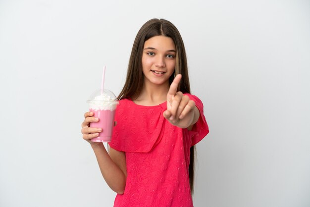 Menina com milk-shake de morango sobre fundo branco isolado, mostrando e levantando um dedo