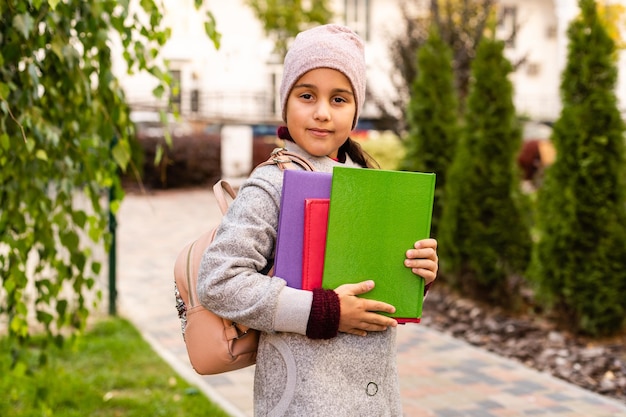 Menina com mochila de brinquedo. Infância feliz. Início do ano letivo. Tempo de outono para estudar. Estudar na escola primária. Conceito de educação escolar. Voltar a estudar.