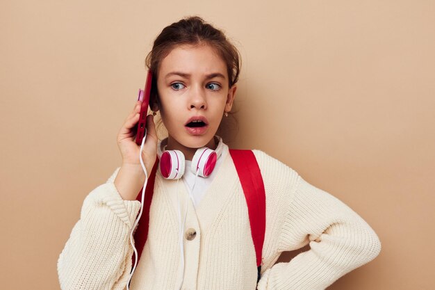 Menina com mochila em fones de ouvido com tecnologia de telefone