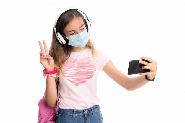 Menina com mochila, headfones e máscara tirando uma selfie