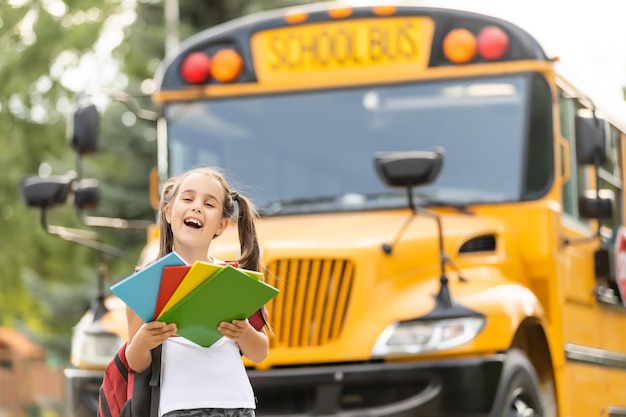 Menina com mochila perto de ônibus escolar amarelo. Transporte para estudantes