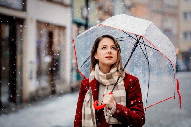 Menina com neve branca de guarda-chuva caindo ficar na rua da cidade