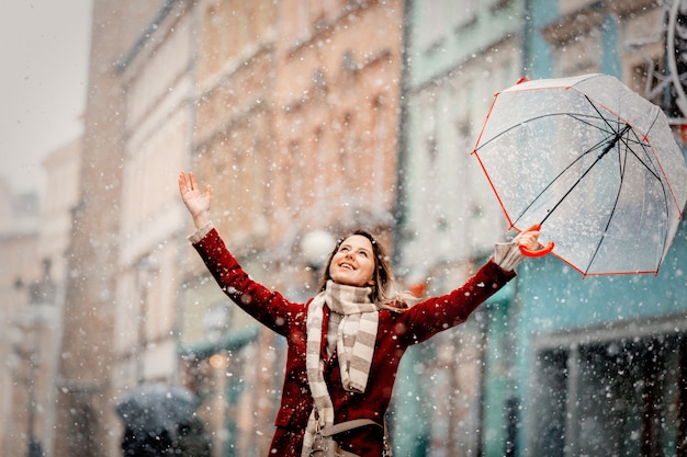 Menina com neve branca de guarda-chuva caindo ficar na rua da cidade
