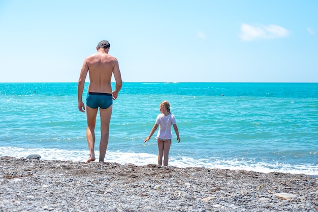 Menina com o pai na costa de Pebble Beach e Blue Sea, férias de verão e viagens