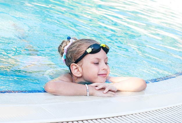 Menina com óculos de natação nadando na piscina