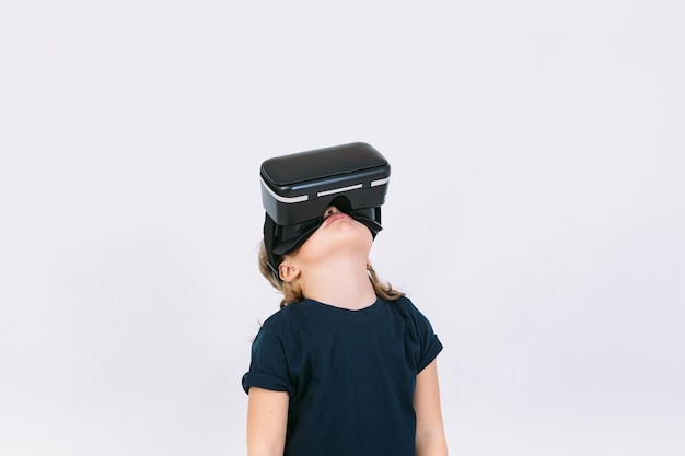 Menina com óculos de realidade virtual olhando para um fundo branco