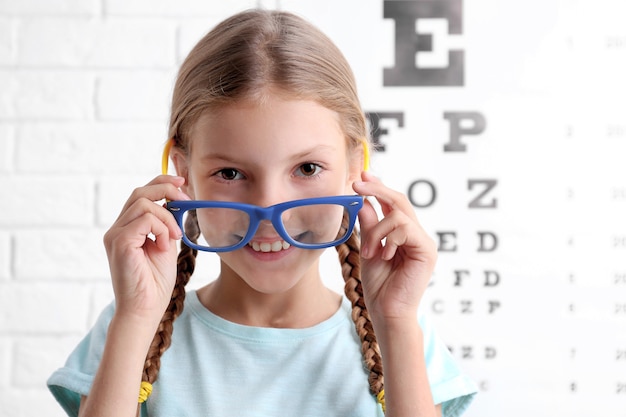 Menina com óculos na ficha de teste oftálmico