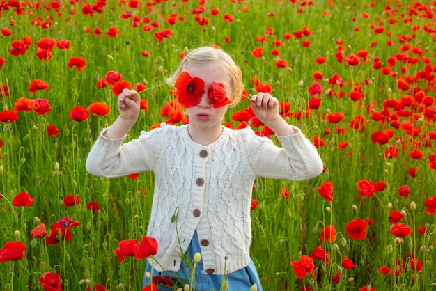 Menina com olhos de papoulas menina descansando em um prado de primavera de papoulas crianças brincam no campo com pop