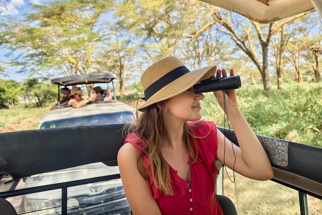 Menina com os binóculos contra o fundo da natureza Observação de pássaros Safári africano de carro com telhado aberto Observação de animais na natureza