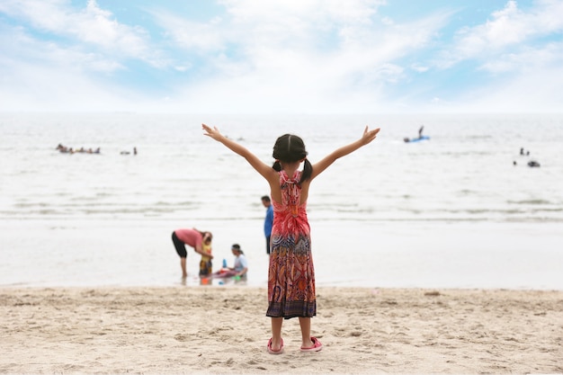 Menina com os braços erguidos na praia