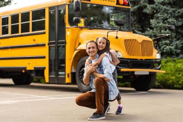 Menina com pai voltando para a escola perto do ônibus escolar