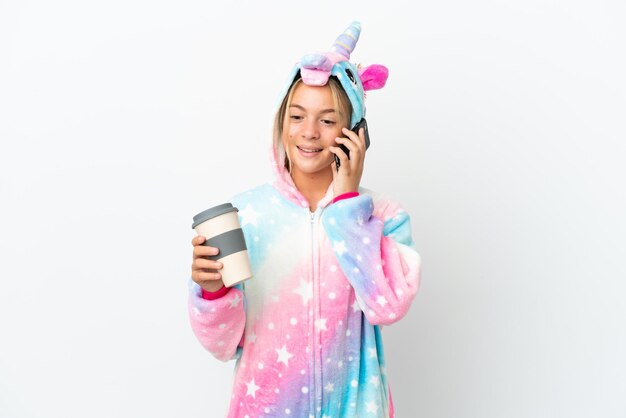 Menina com pijama de unicórnio isolado no fundo branco segurando café para levar e um celular