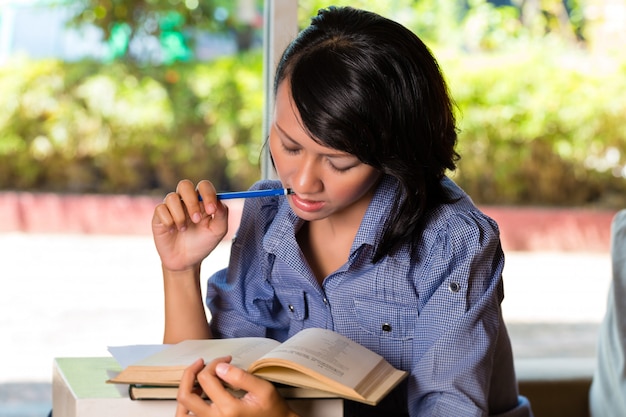 Menina com pilha de livros de aprendizagem