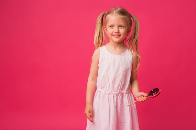 Menina com pirulito em fundo rosa