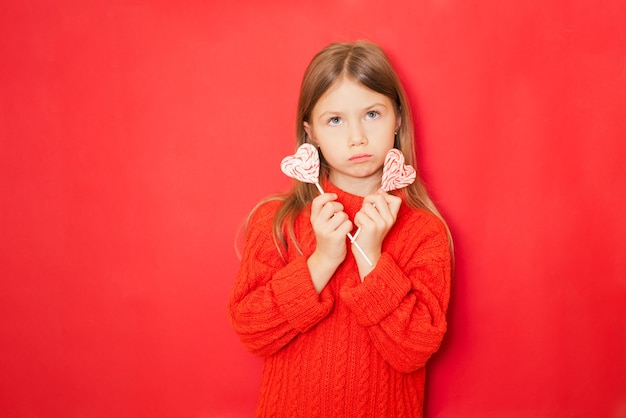 Menina com pirulitos em um fundo vermelho