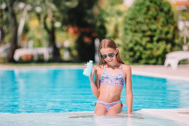 Menina com protetor solar na piscina