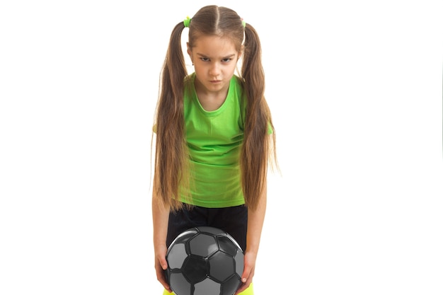 Menina com raiva joga futebol com a bola isolada no fundo branco