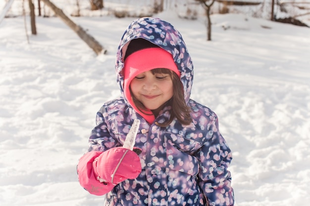 Menina com roupas de inverno provando o gelo
