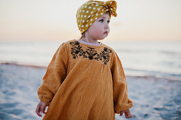 Menina com roupas orientais caminhando na praia ao pôr do sol