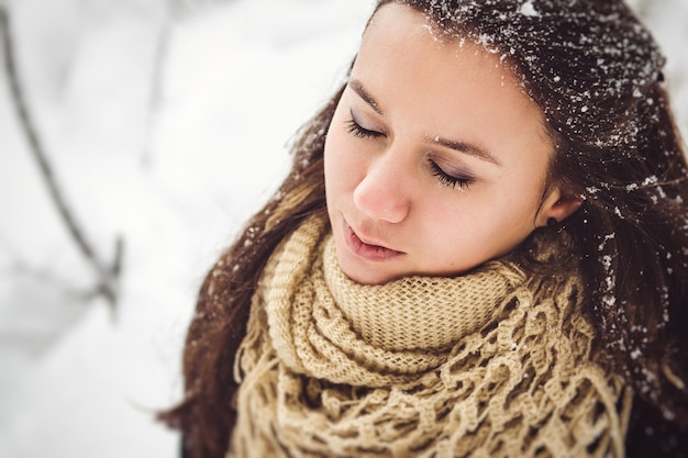 Menina com roupas quentes e lenços em uma caminhada no bosque nevado e no campo