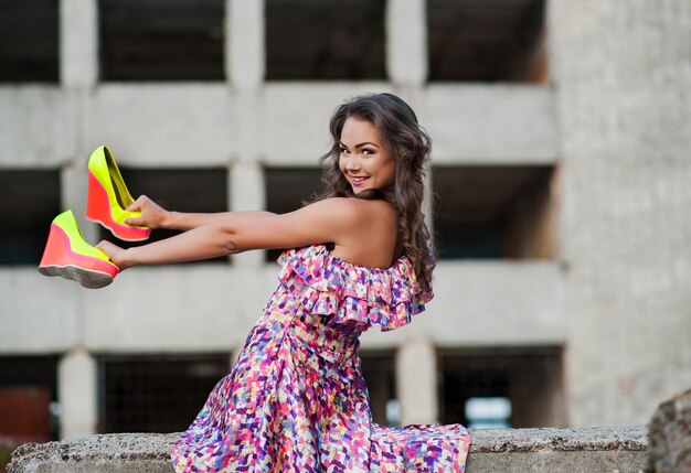 Menina com sapatos nas mãos fazendo gestos sorrindo