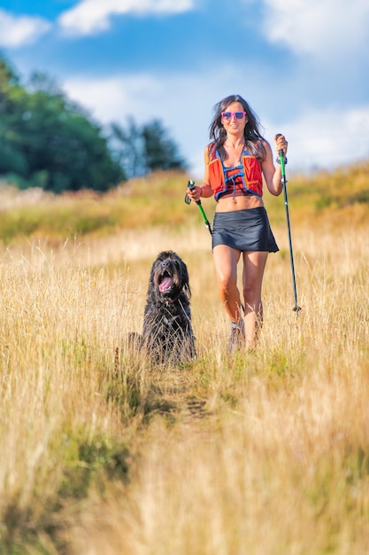 Menina com seu cachorro em uma caminhada nórdica