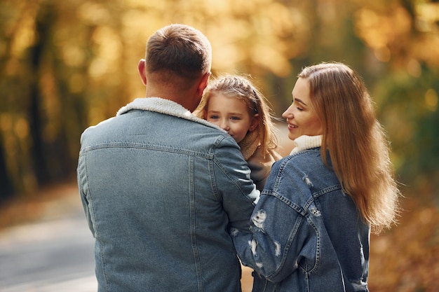 Menina com seus pais Família feliz está no parque no outono juntos