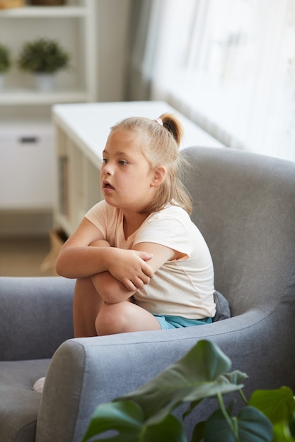 Menina com síndrome de down sentada na poltrona e descansando na sala de estar