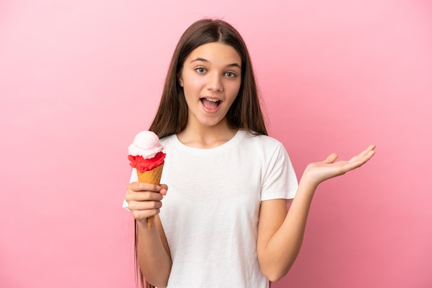 Menina com sorvete de corneta sobre fundo rosa isolado com expressão facial de choque