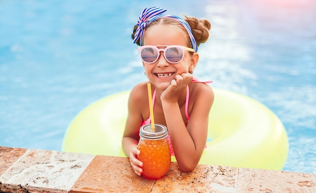 Menina com suco de laranja na piscina