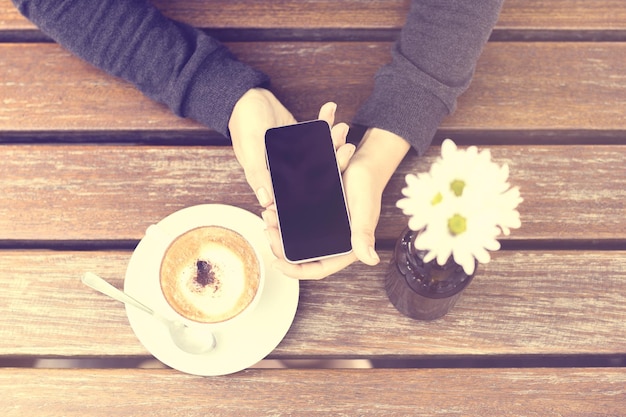 Menina com telefone celular e xícara de café