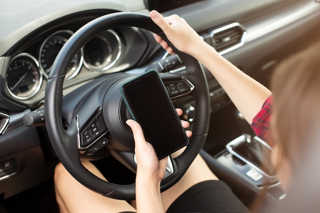 Menina com telefone inteligente no carro