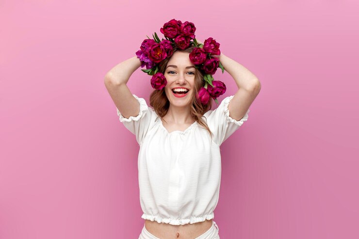 Foto menina com tulipas cor de rosa em seu cabelo sorri em fundo rosa isolado mulher com flores na cabeça