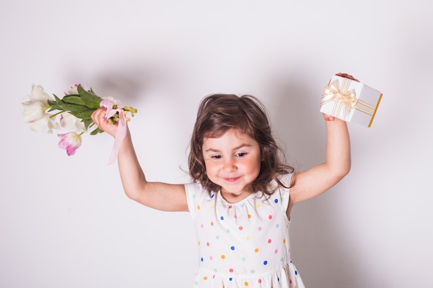 Menina com tulipas e caixa com presente para a mãe