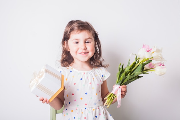 Menina com tulipas e caixa com presente para a mãe
