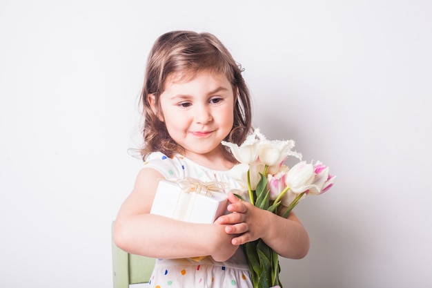 Menina com tulipas e caixa com presente para a mãe