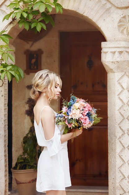 Menina com um buquê de flores nas mãos dela está esperando por seu amado homem perto de casa.