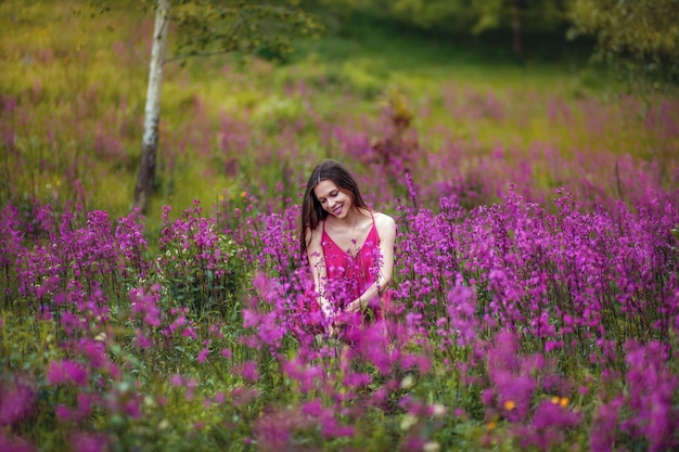 Foto menina com um buquê de flores, prado verde, flores roxas e rosa